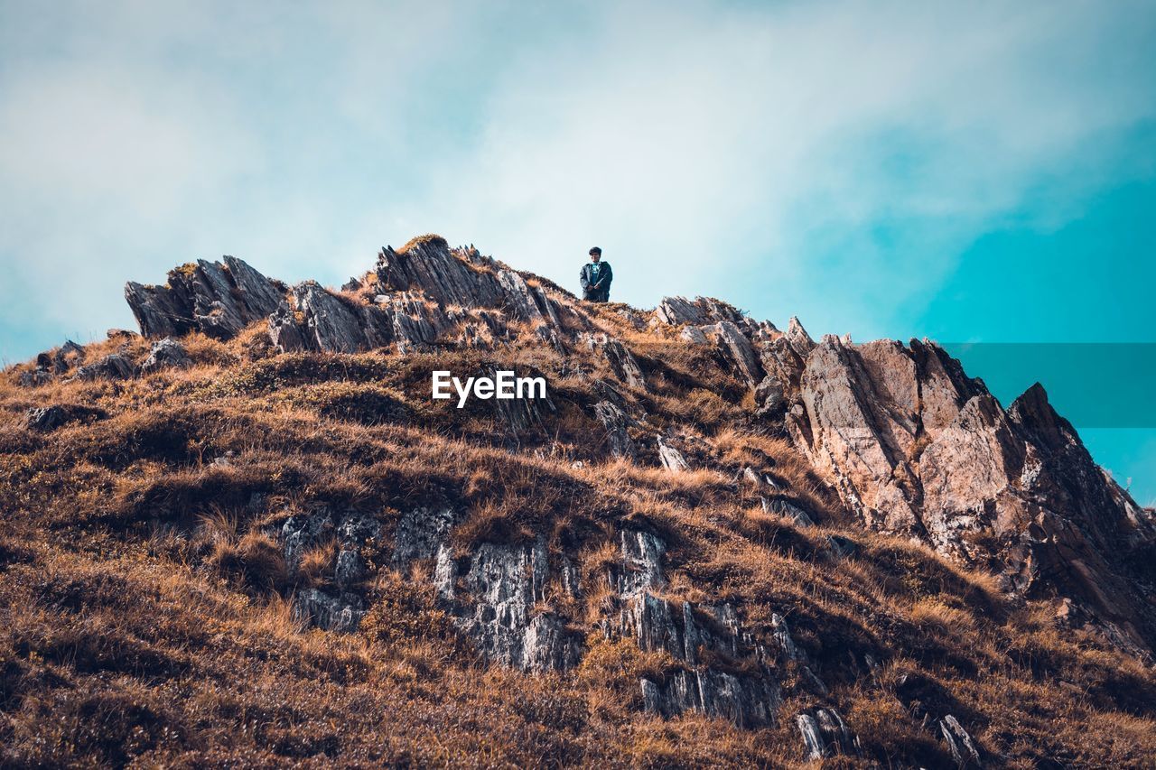 Low angle view of man on cliff against sky