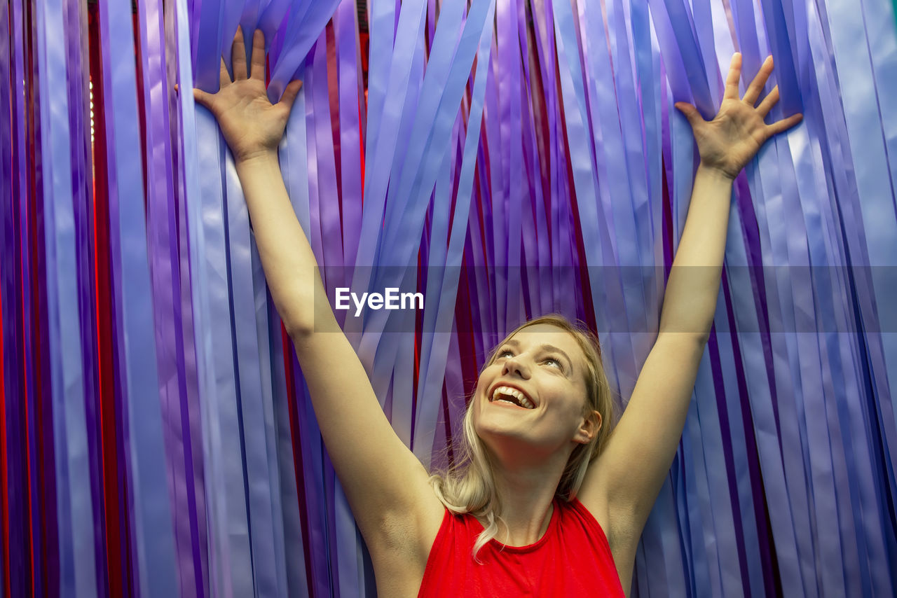 Smiling young woman standing against curtain