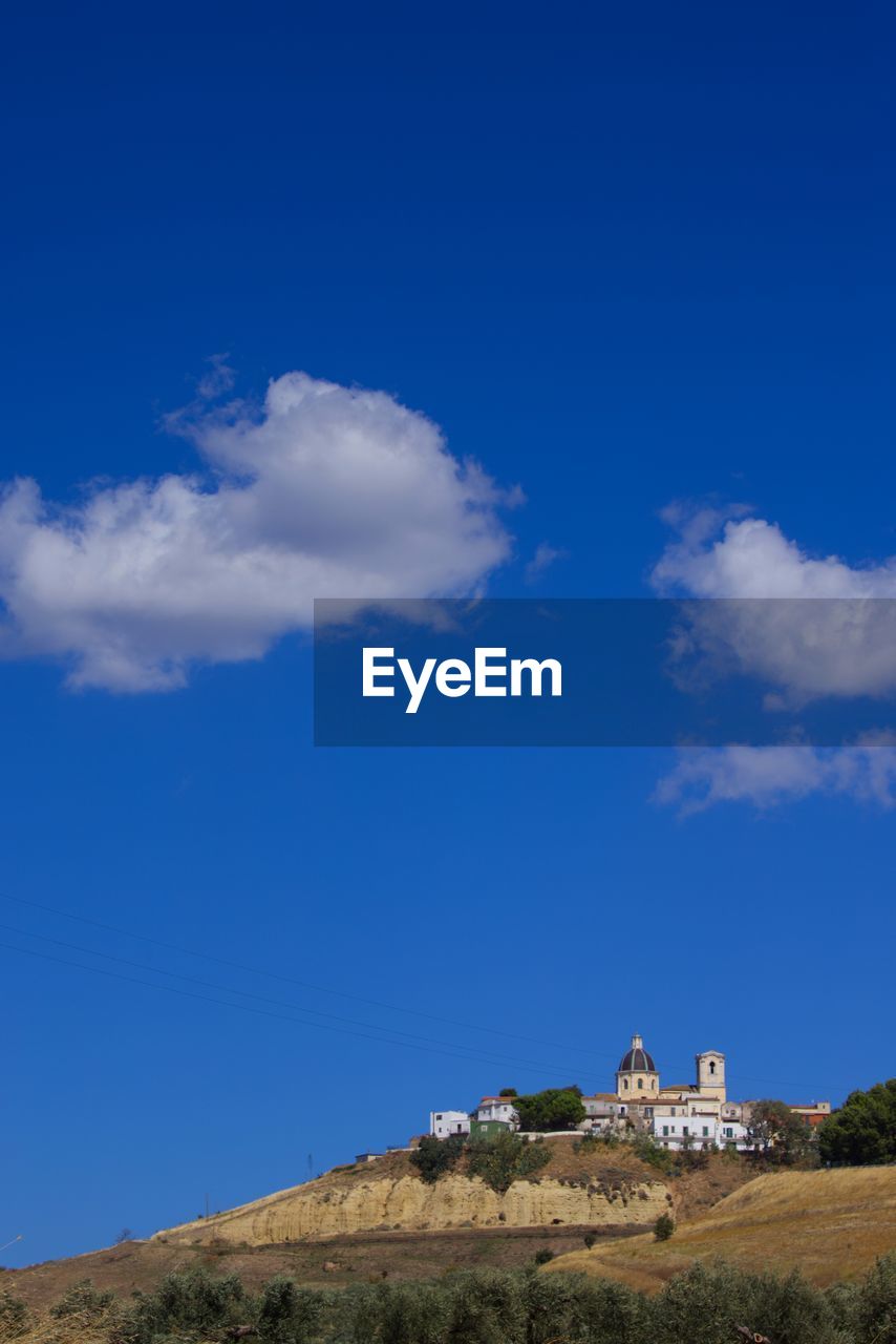 sky, blue, architecture, horizon, cloud, built structure, hill, nature, building exterior, travel destinations, building, environment, travel, landscape, history, no people, scenics - nature, the past, tourism, land, religion, sea, plant, beauty in nature, outdoors, place of worship, house, day, belief, copy space, tranquility, tower, tree, spirituality