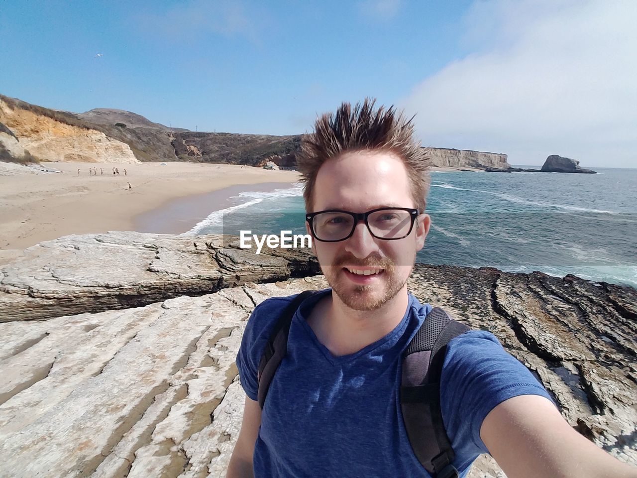 Portrait of man smiling while standing on rocky shore at beach