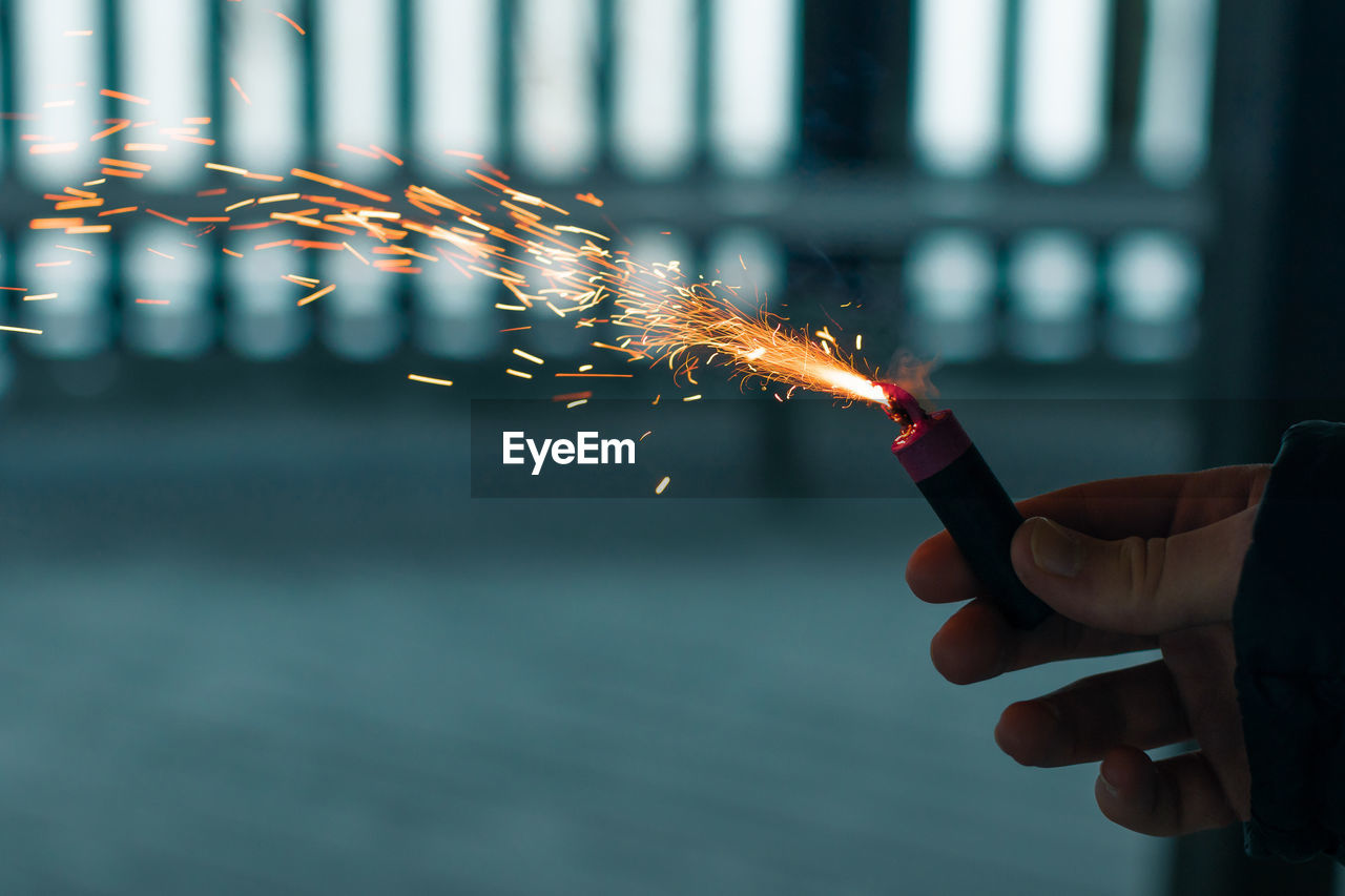 Burning firecracker with sparks. guy holding a petard in a hand