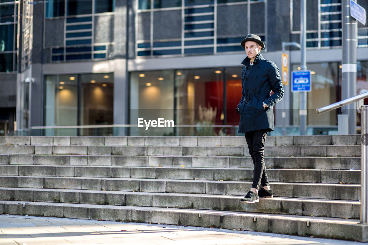 Portrait of man standing on steps in city