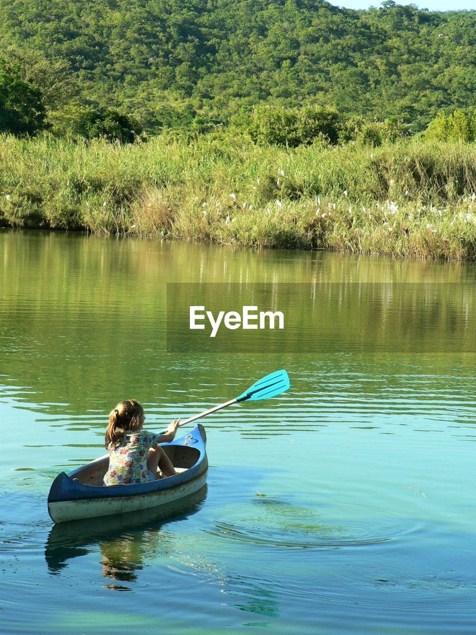 Rear view of girl oaring boat in lake