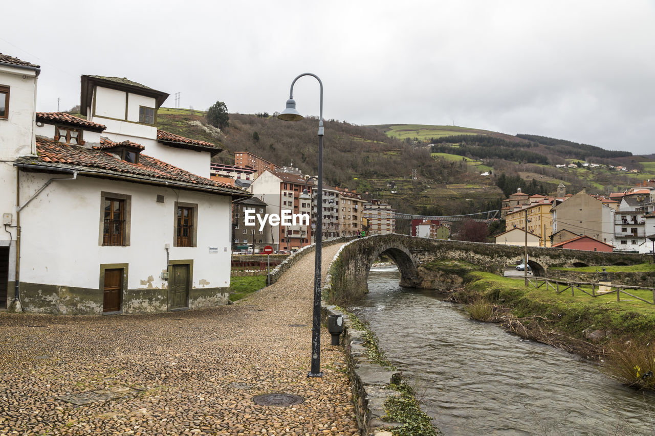 Bridge over canal amidst buildings against sky