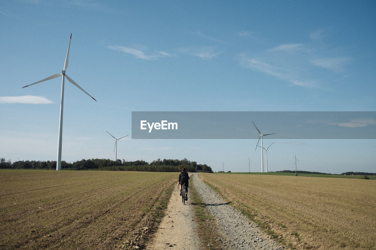 Cyclist on a gravel road, between fields.