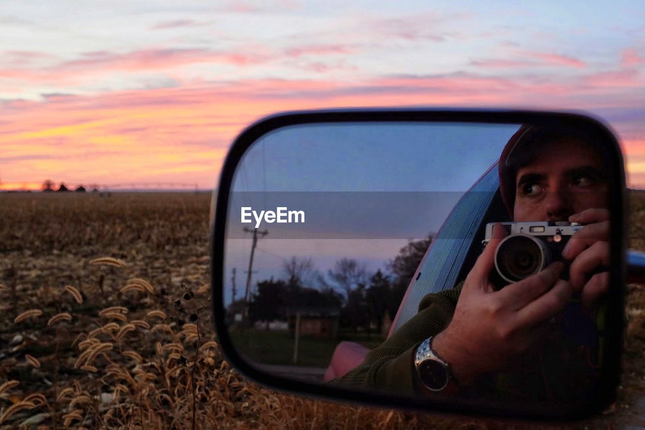 Reflection of man photographing through mirror