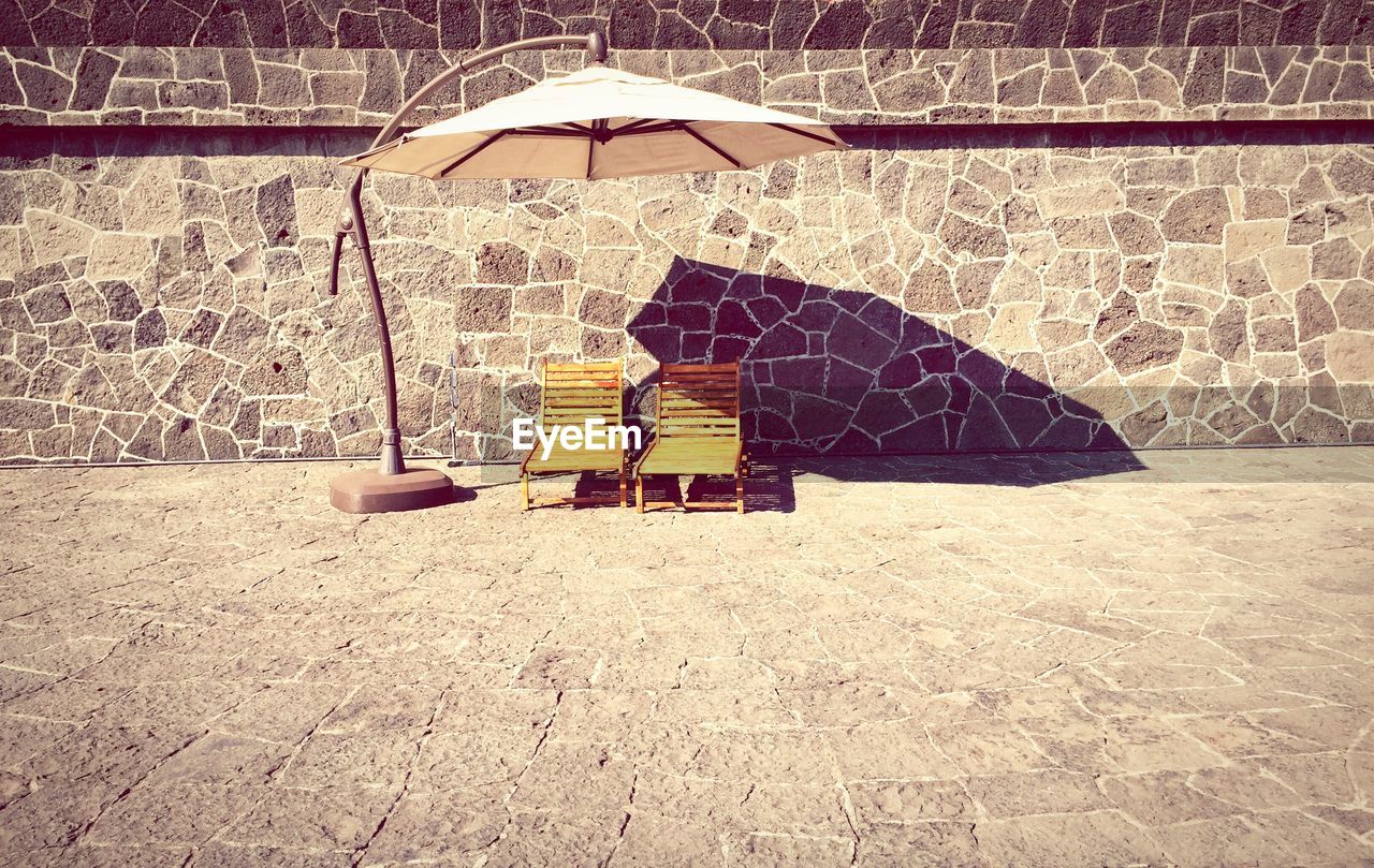 Empty deck chairs with parasol by wall