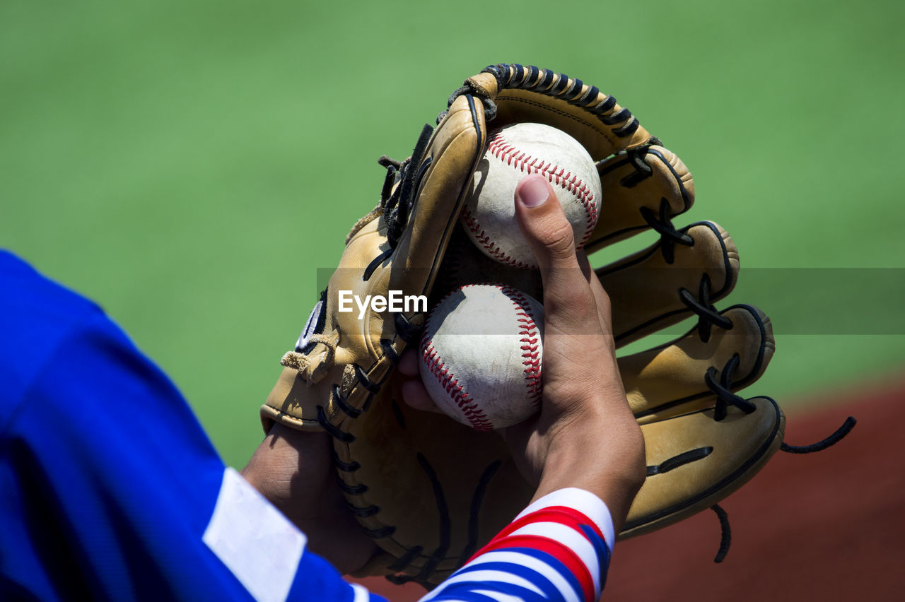 Midsection of baseball player holding glove and balls
