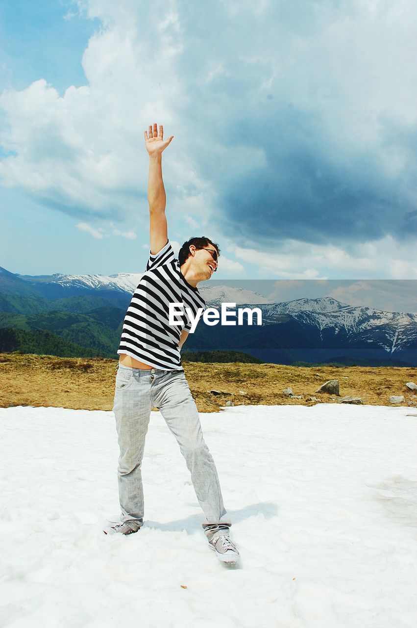 Man standing on snow covered field against cloudy sky