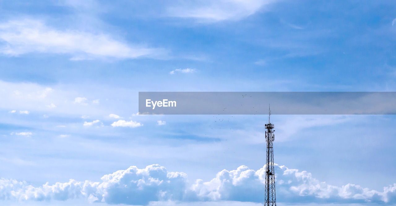 Mobile telecommunication tower with communication antennas in the background of dense clouds