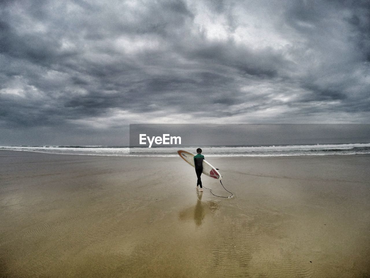 MAN STANDING ON BEACH AGAINST SKY