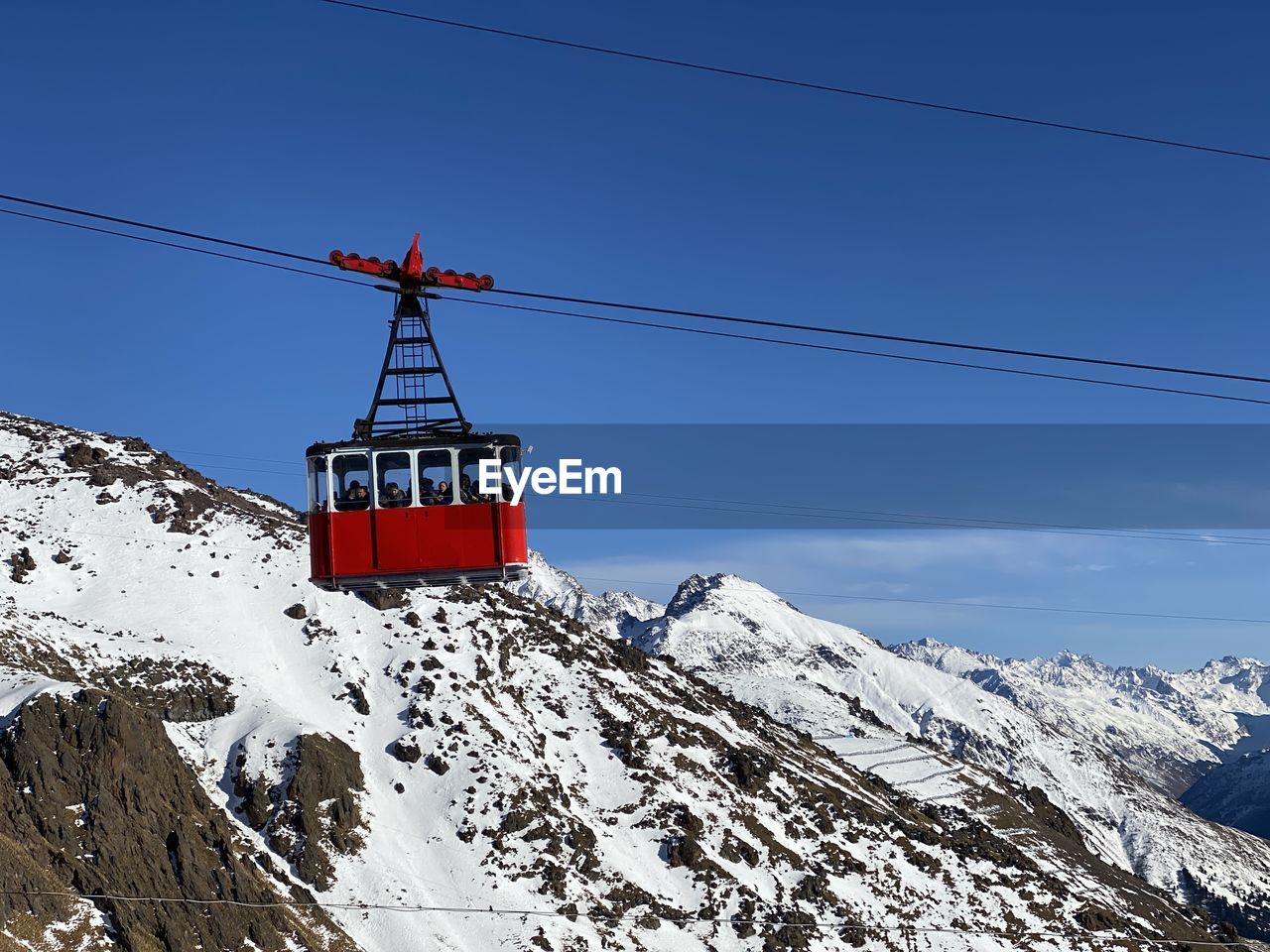 OVERHEAD CABLE CAR OVER SNOWCAPPED MOUNTAIN AGAINST SKY