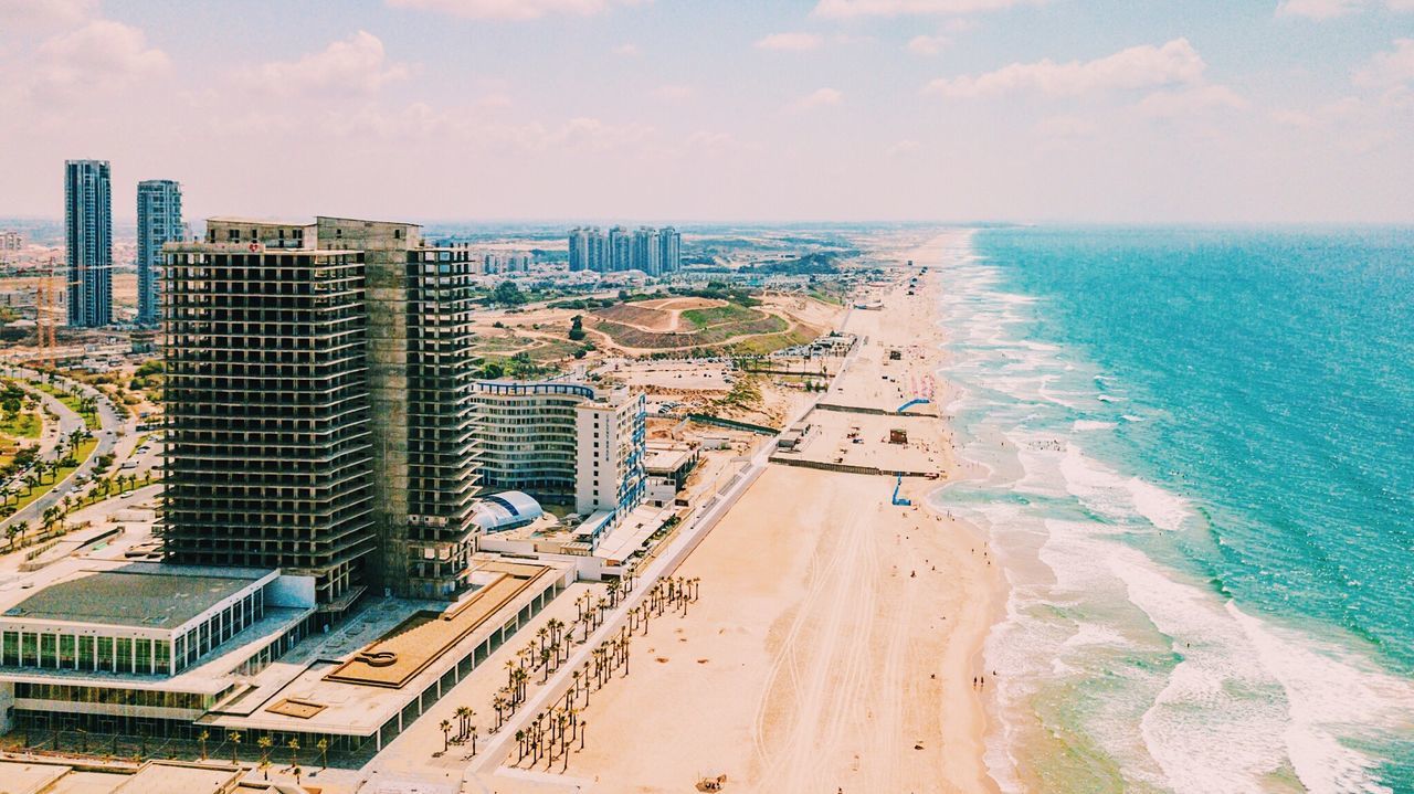 Aerial view of city by sea against sky