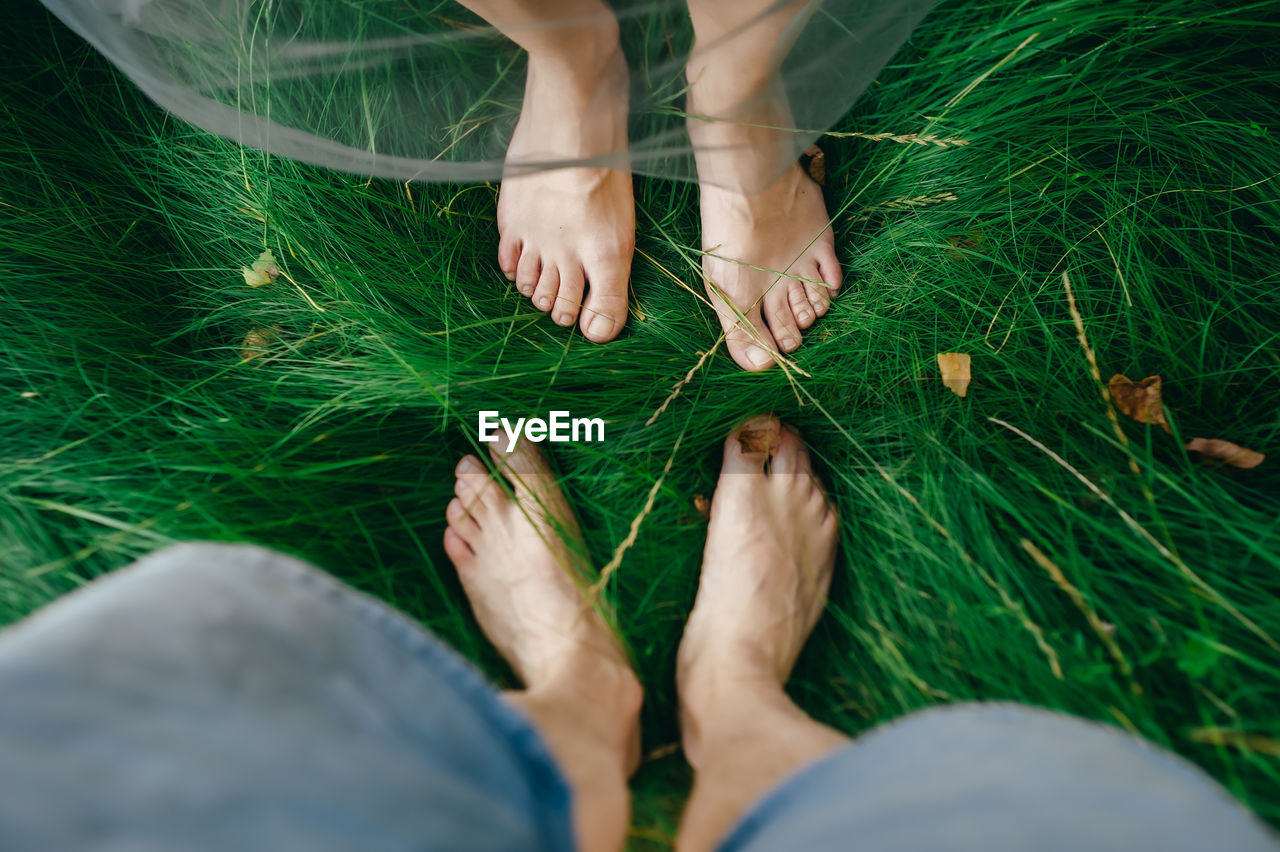 LOW SECTION OF WOMAN WITH LEGS ON GRASS