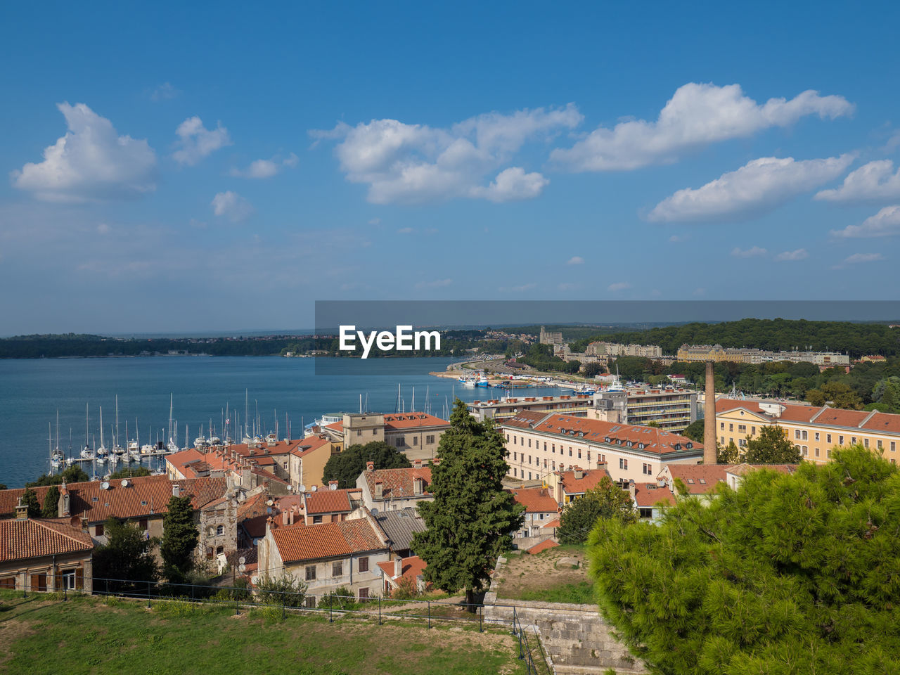 Town by sea against cloudy sky