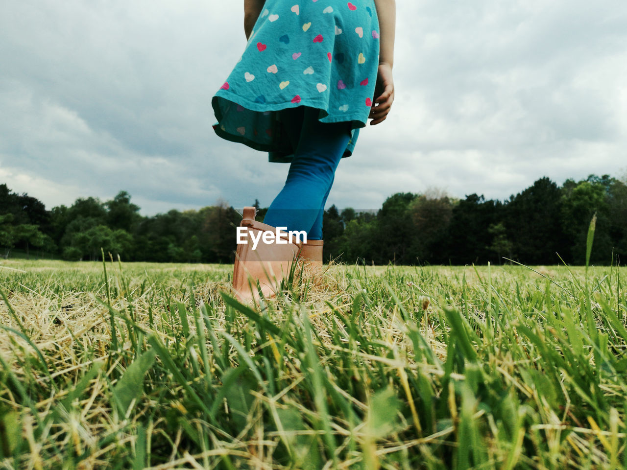 Low section of woman standing on field against sky