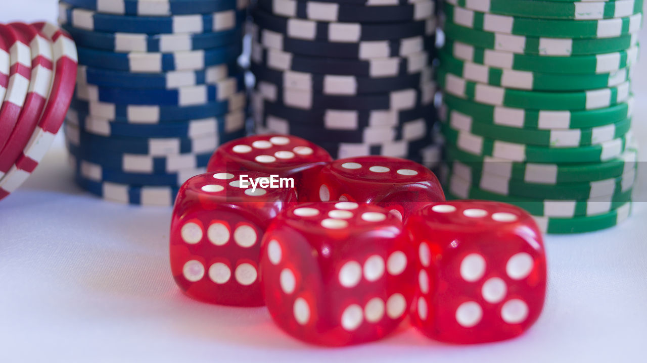 Close-up of red dice and gambling chips on white table