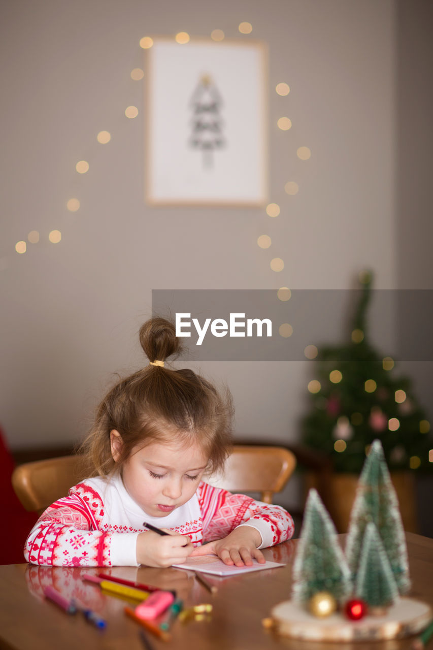 Girl in illuminated christmas tree at home