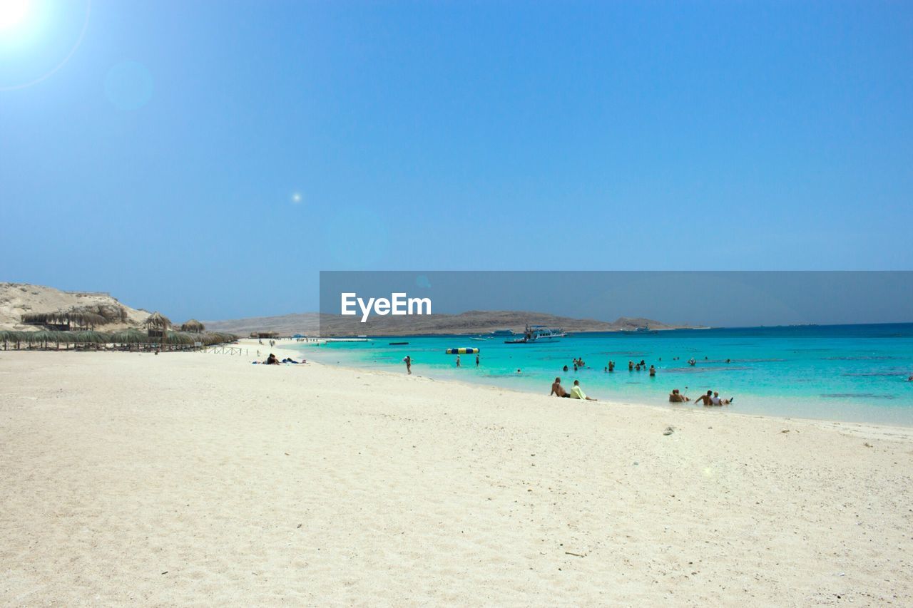 PEOPLE AT BEACH AGAINST CLEAR BLUE SKY