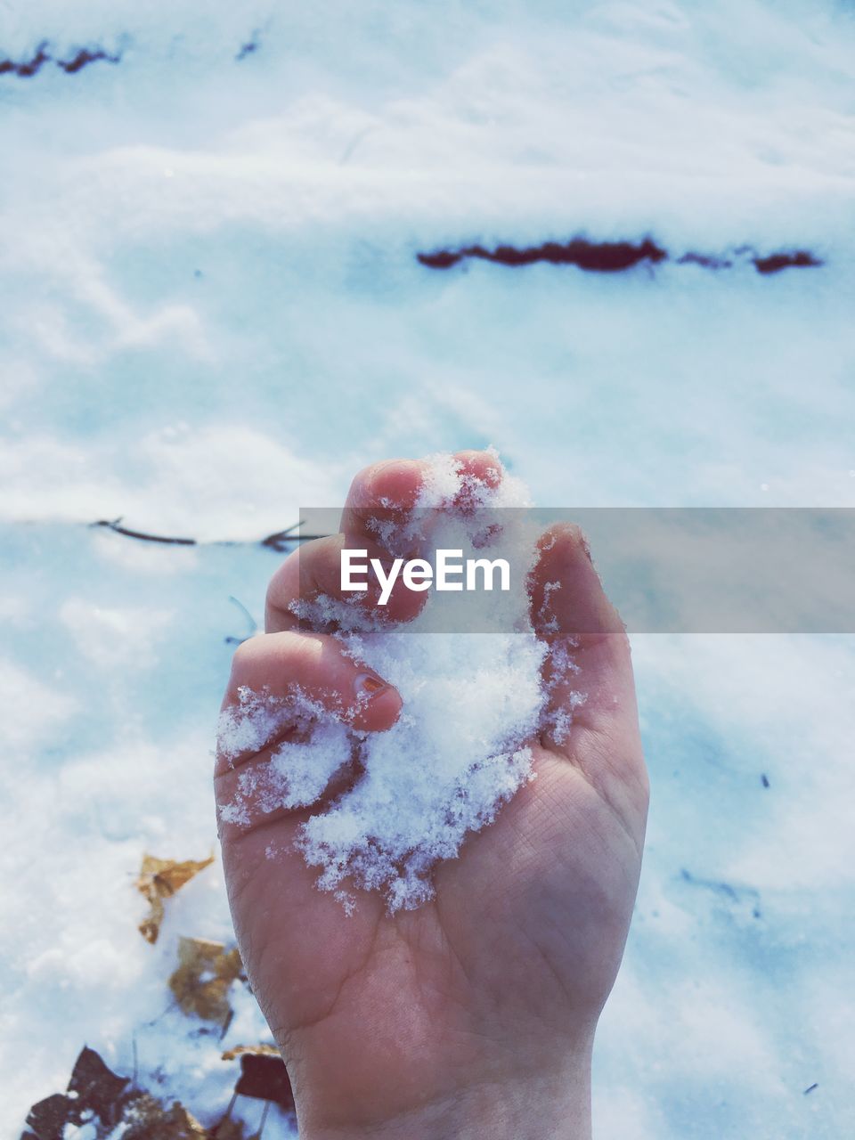 CLOSE-UP OF HAND HOLDING ICE CREAM AGAINST SKY