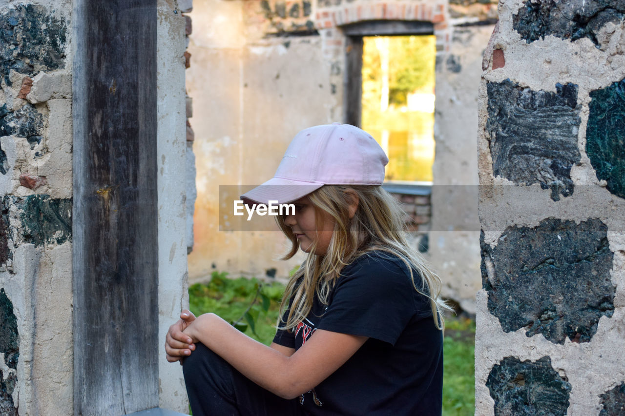 Side view of girl standing against built structure