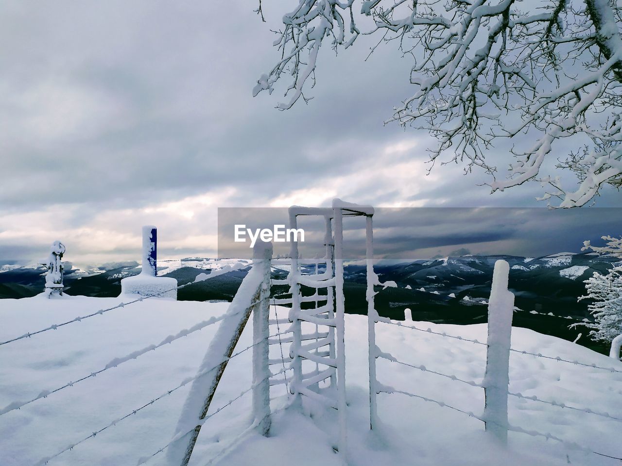 SNOW COVERED WOODEN FENCE ON FIELD AGAINST SKY