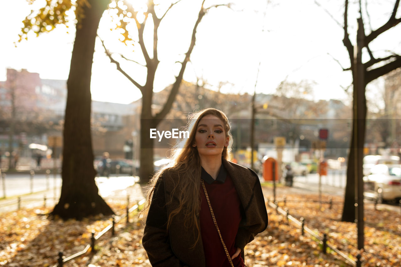 Portrait of young woman standing against trees