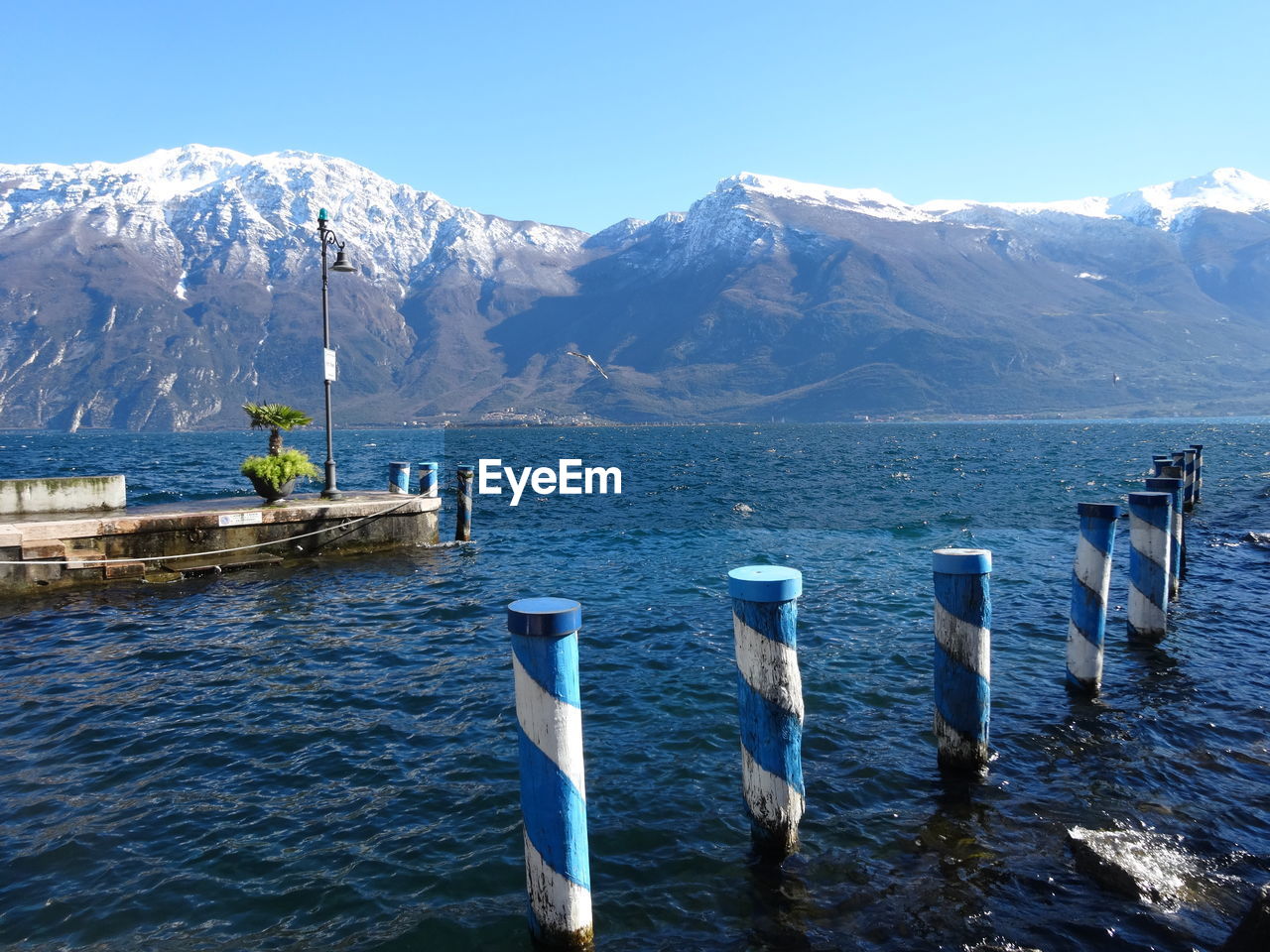 WOODEN POSTS IN SNOWCAPPED MOUNTAINS AGAINST SKY