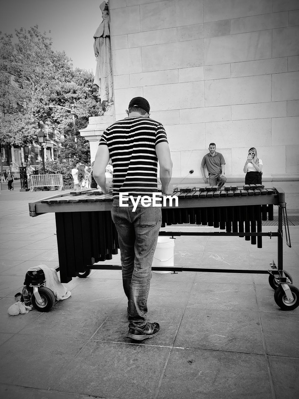 Rear view of man playing musical equipment while standing on road