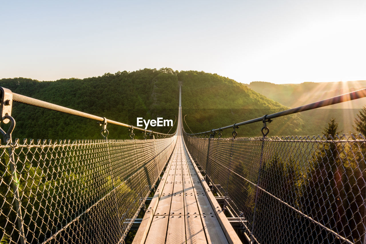 Suspension bridge and mountain against sky