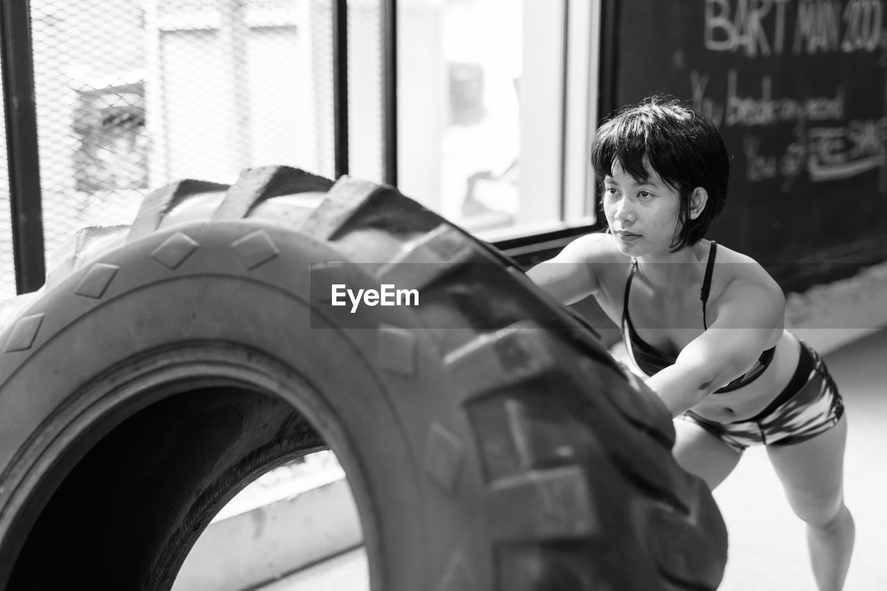 Young woman exercising with tire at home