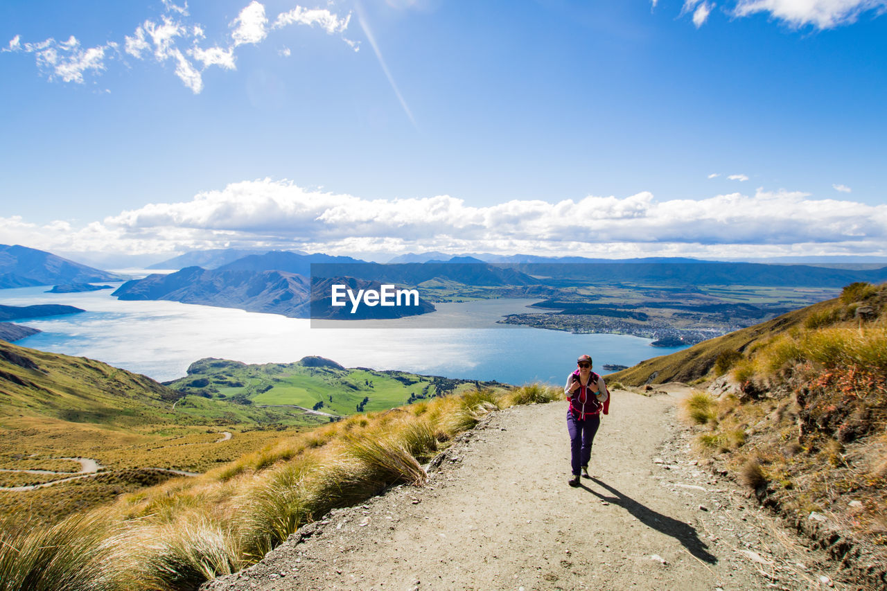 Full length of woman walking on mountain against sky during sunny day