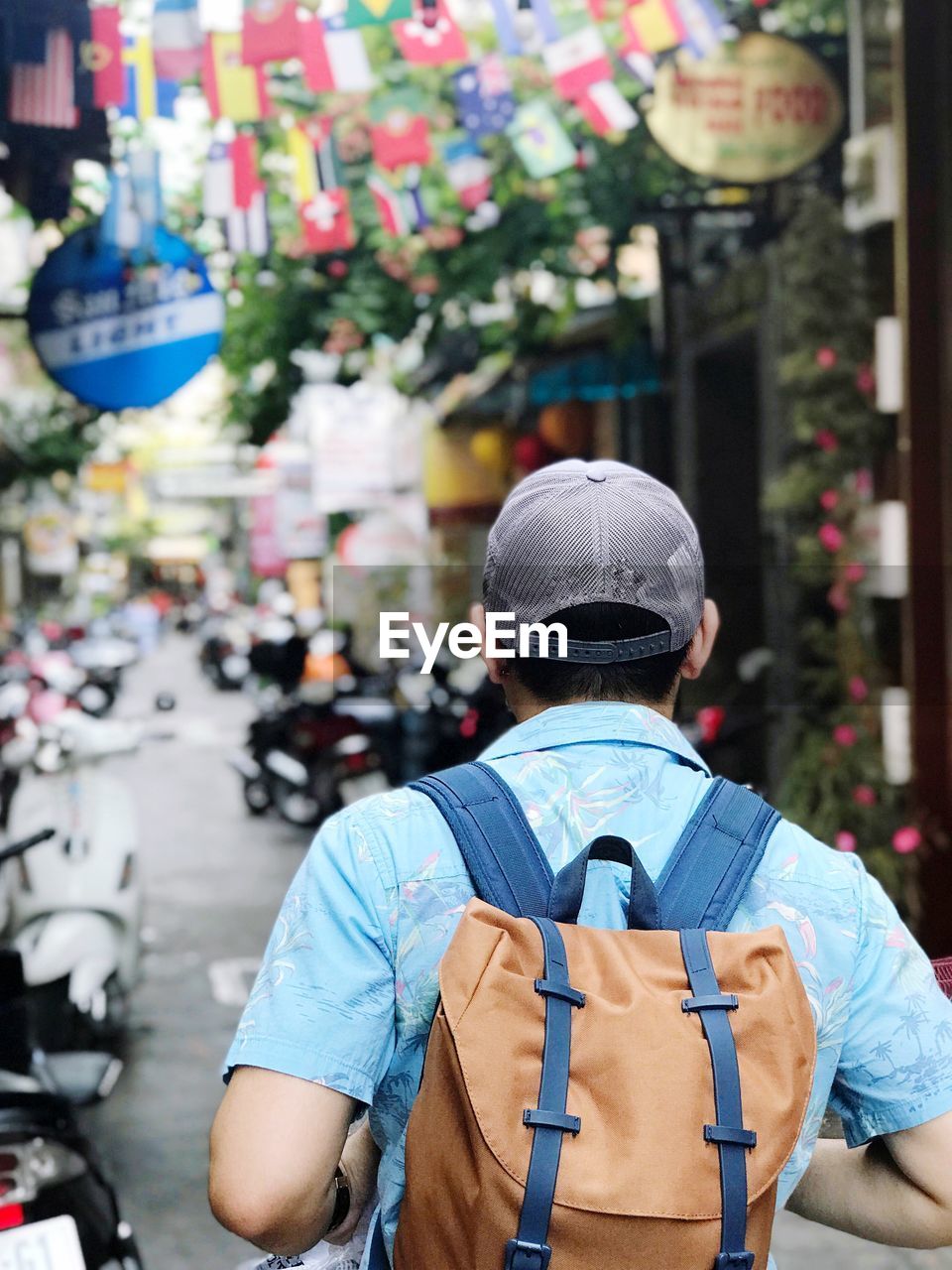 The man bag packer is looking for accommodation in vietnam. rear view of man standing in city