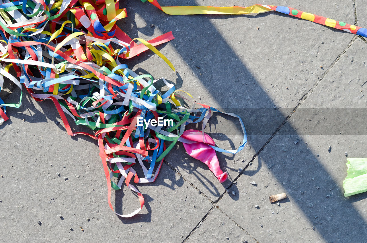 High angle view of colorful tangled confetti on footpath with shadow