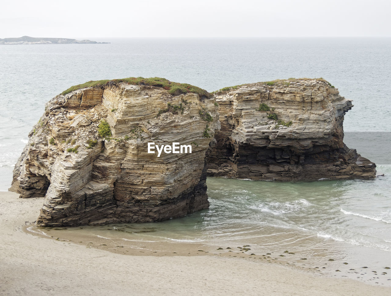 Rock formation on beach against sky