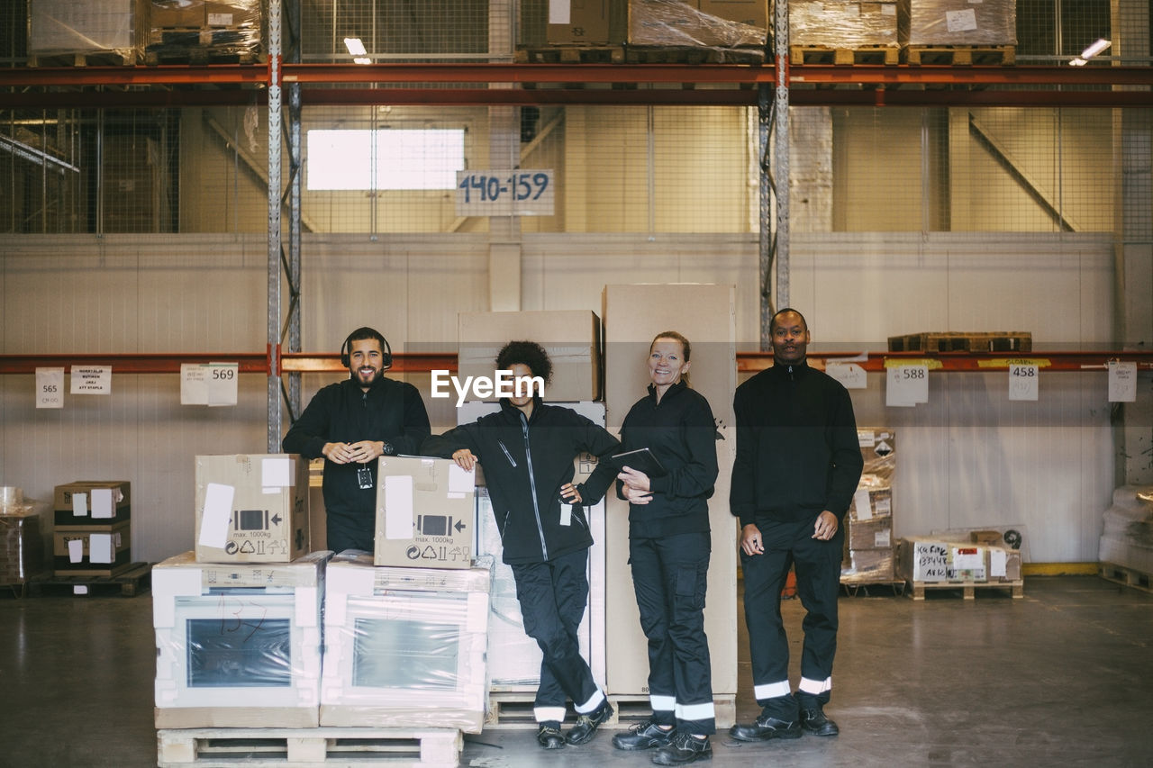 Portrait of smiling warehouse workers standing with box containers