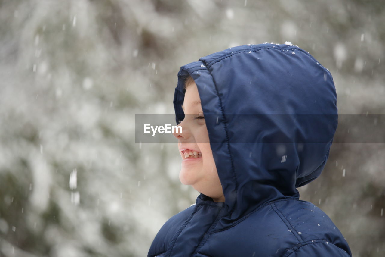 Close-up of smiling boy enjoying snowfall