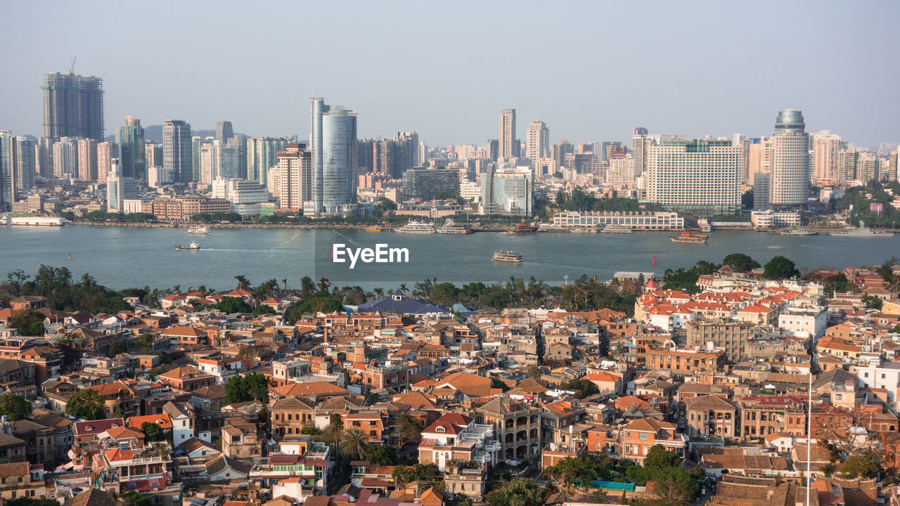 Cityscape by sea against clear sky
