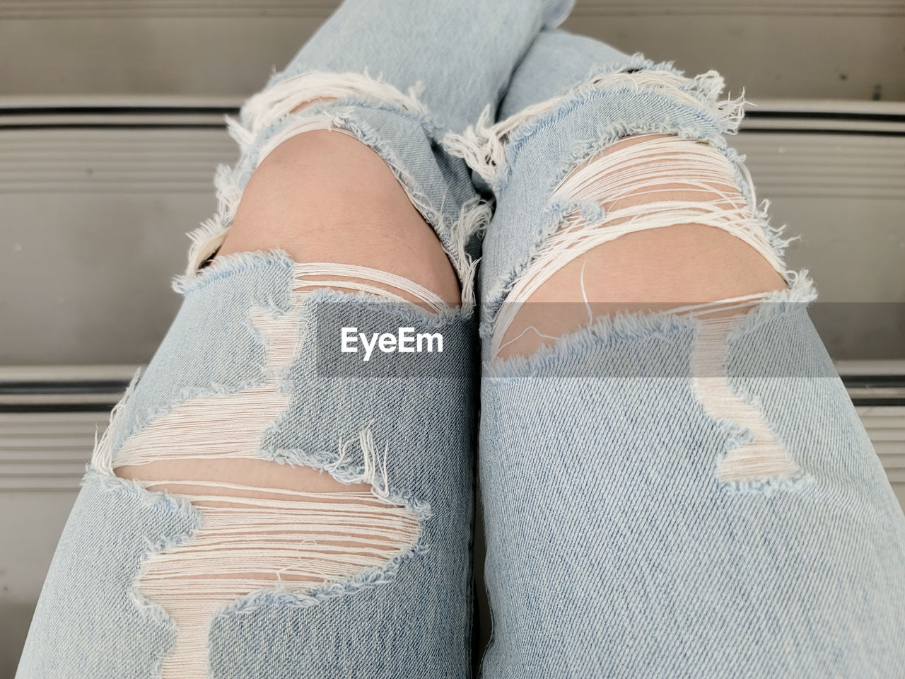 Low section of woman wearing torn jeans