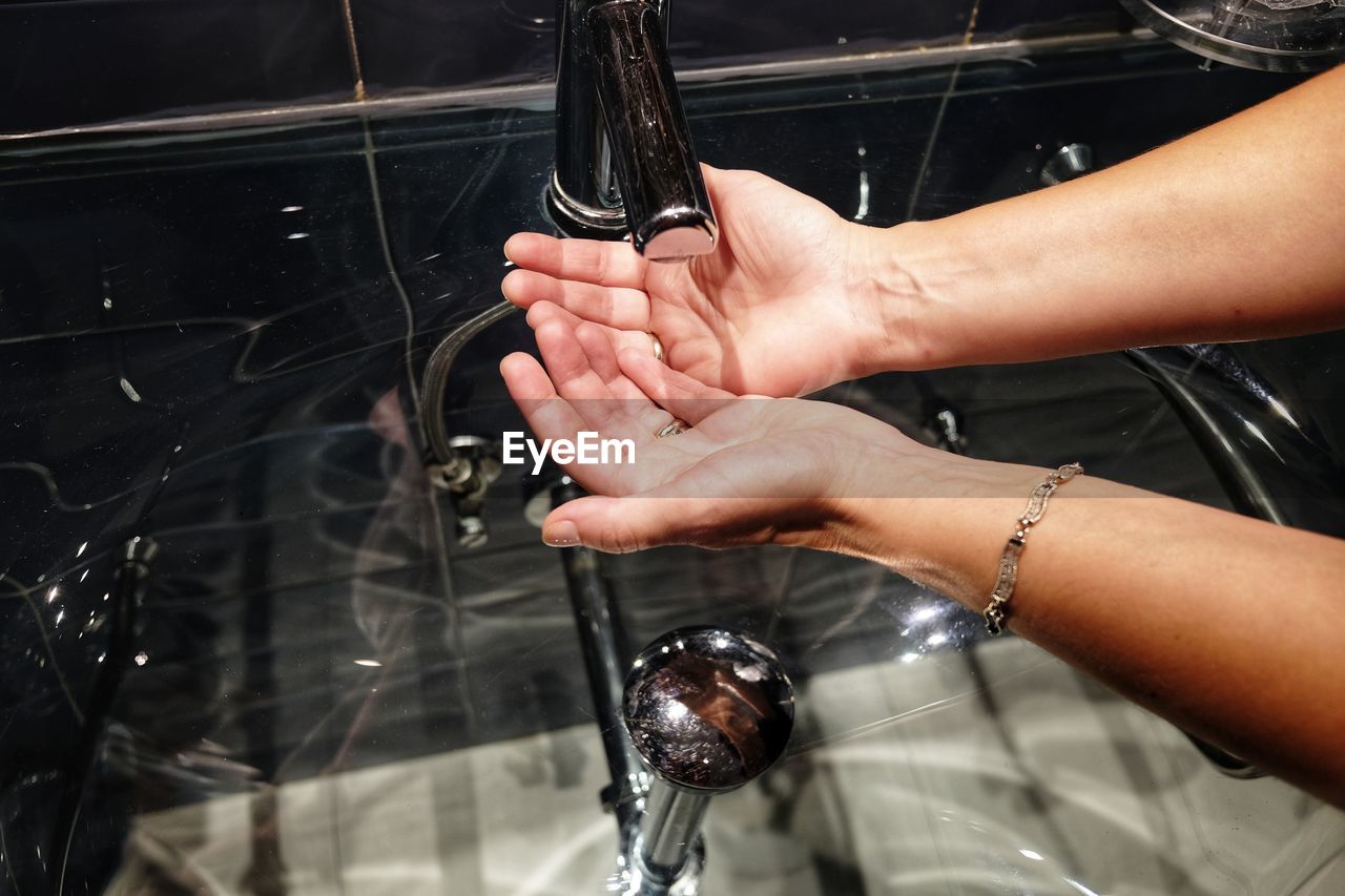 Cropped hands of woman washing hands in sink