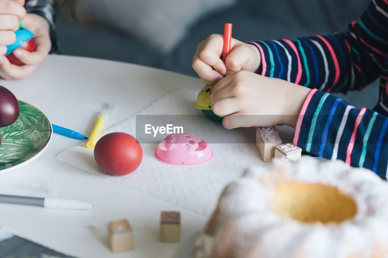 Close-up of girl holding multi colored pencils on table