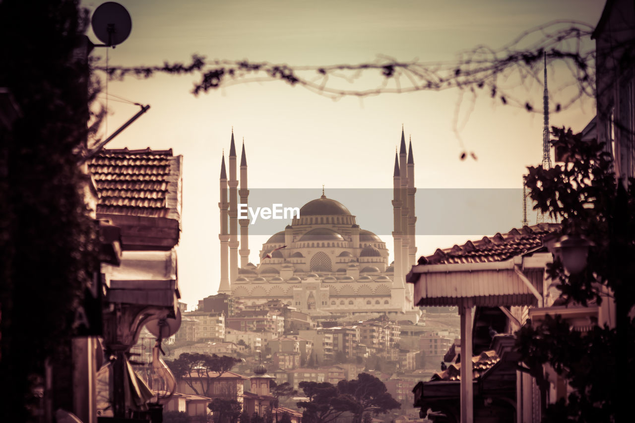 Mosque in city against sky