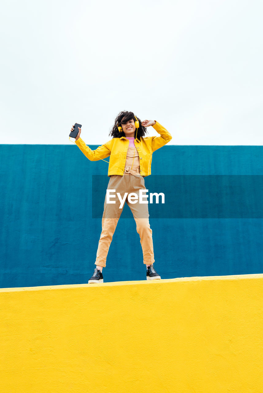 Woman standing on yellow wall