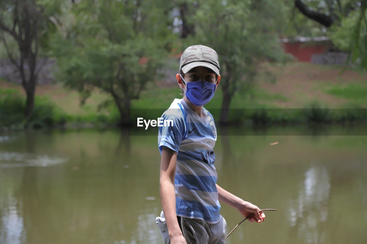 Portrait of boy wearing mask standing by lake