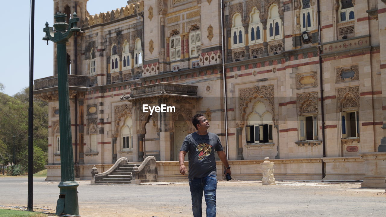 YOUNG MAN STANDING AGAINST BUILDING