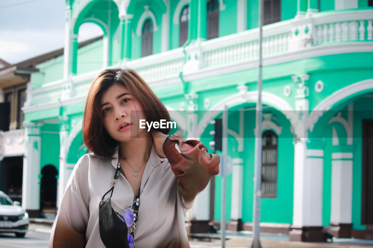 Portrait of beautiful woman standing against building