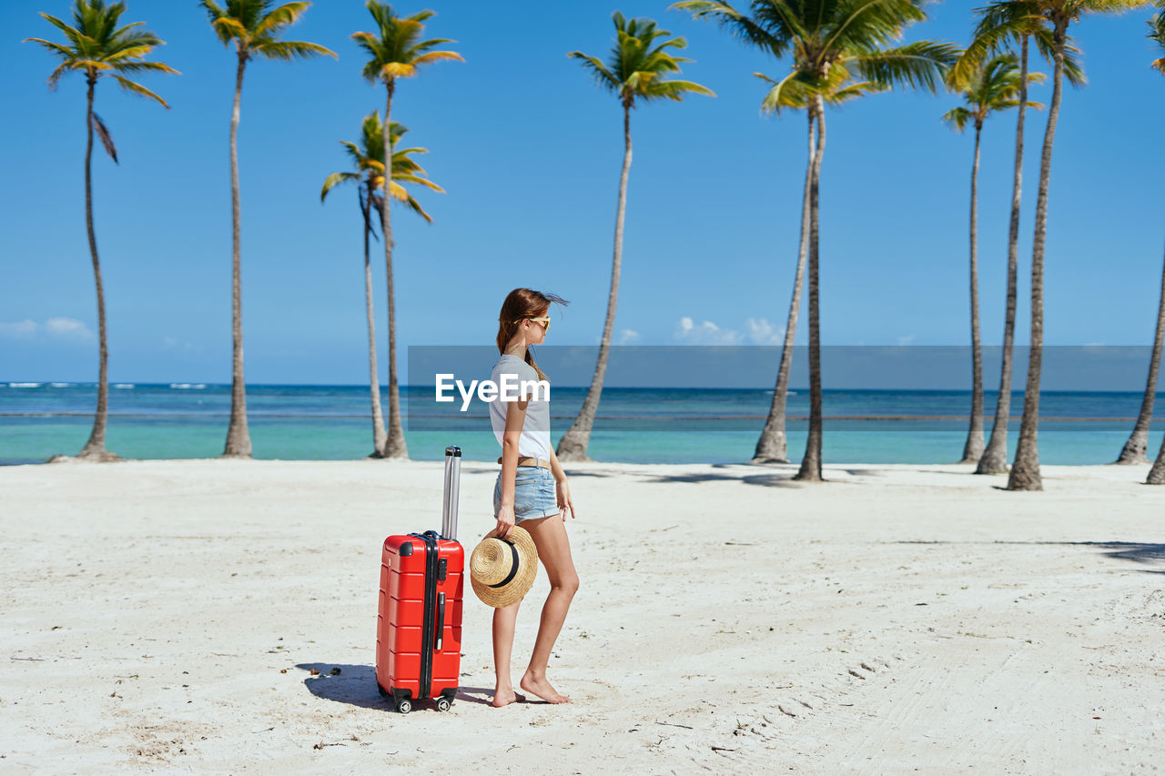 YOUNG WOMAN ON BEACH AGAINST SKY