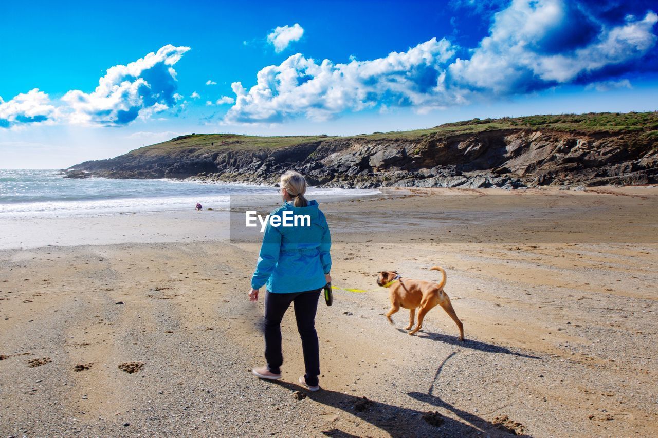 Woman standing with dog at shore of beach