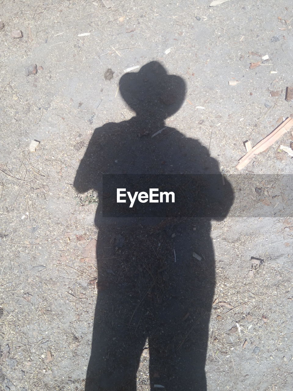 Shadow of man standing on dirt field