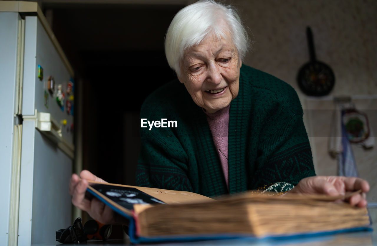 Portrait of old woman looking album at home